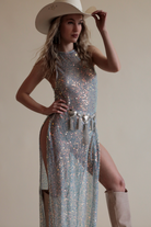 Sequin maxi top with high neckline and high slits paired with chain heart fringe belt and cowboy hat.