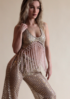 Beige macrame fringe halter top and matching mirror sequin pants.
